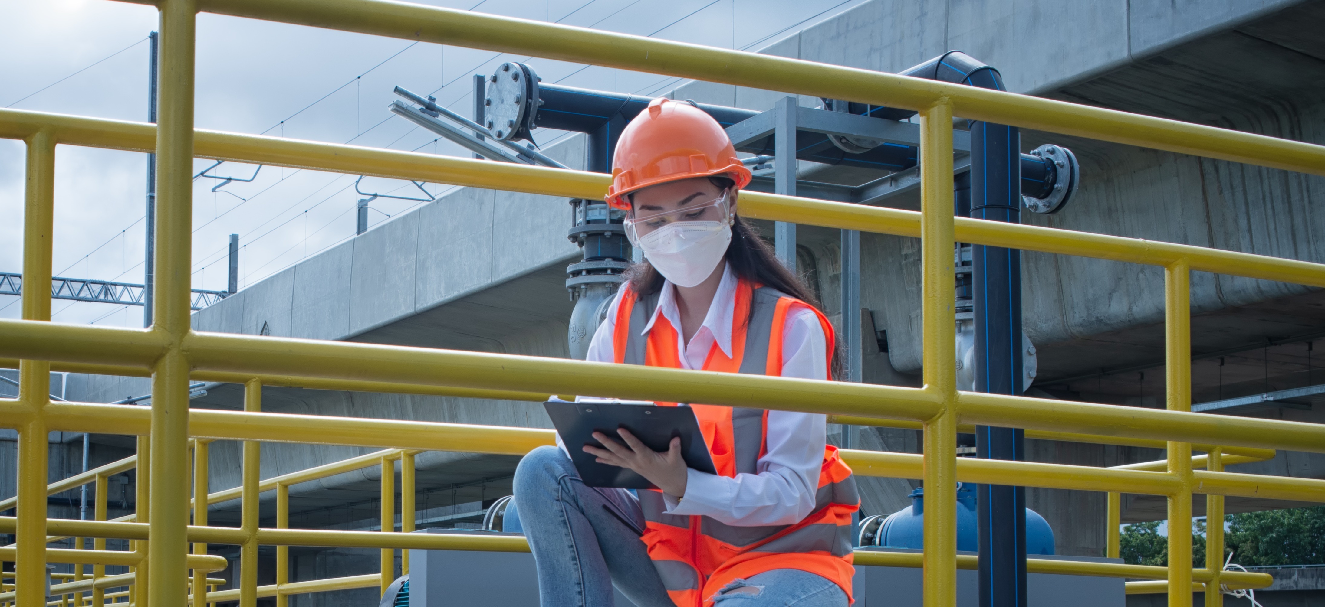 A woman inspecting a handrail and walkway system at a water treatment plant