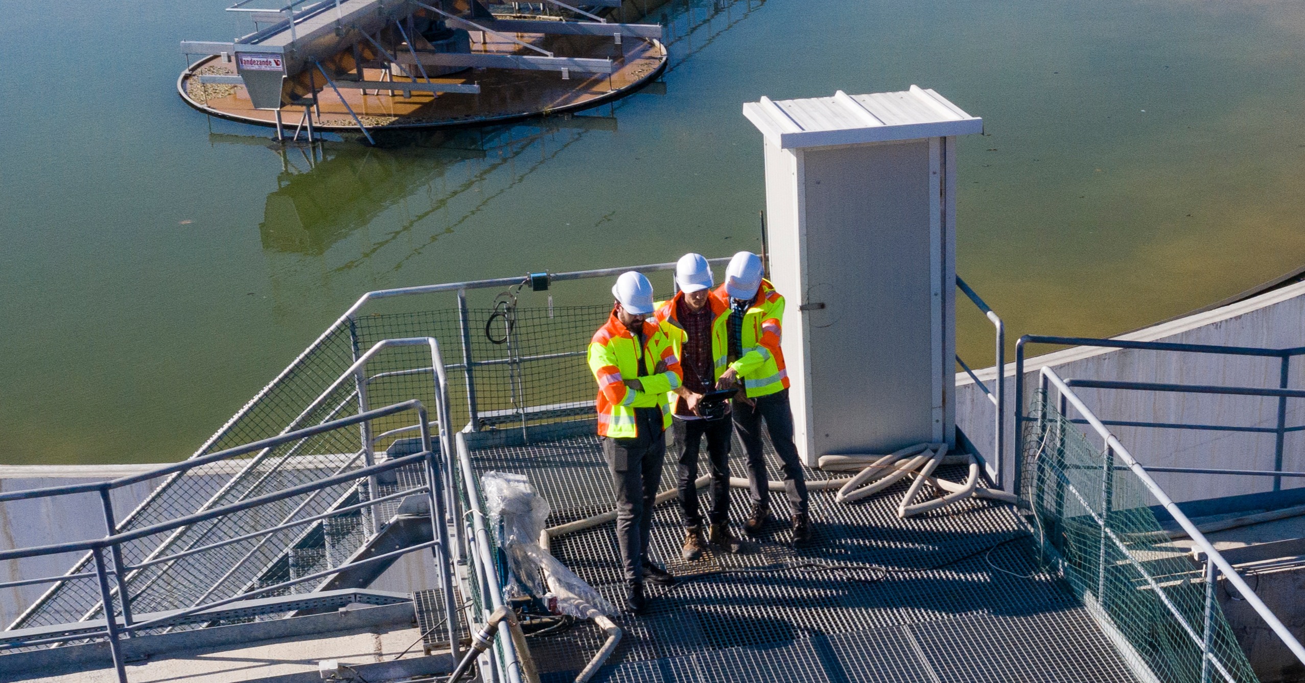 Three workers standing on an aluminum walkway at a water treatment plant